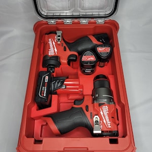 May include: A red Milwaukee tool case with two cordless drills and two batteries. The drills are a Fuel 12V impact driver and a 12V hammer drill. The case has a clear lid.