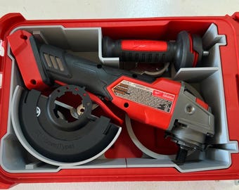May include: A red and black cordless angle grinder with a gray cutting wheel, a black guard, and a red handle. The grinder is in a red and gray plastic case.