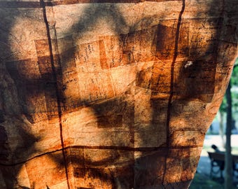 May include: Close-up of a textured, brown paper lantern with a grid-like pattern. The lantern is lit from behind, casting shadows and highlighting the paper's texture. The overall effect is warm and inviting, suggesting a handmade craft.