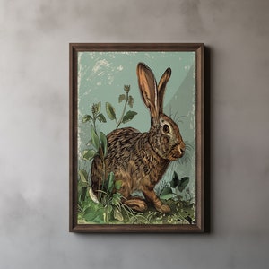May include: A framed art print featuring a detailed illustration of a brown rabbit amidst green foliage. The artwork has a vintage aesthetic with a light blue background and a dark brown wooden frame. The rabbit has long ears and is surrounded by plants.