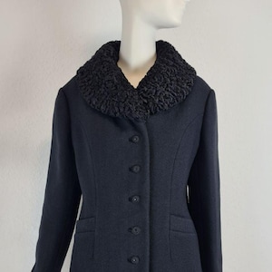 May include: A navy blue jacket with a textured black collar. The jacket has a button-up front, long sleeves, and two front pockets. The jacket is displayed on a mannequin.