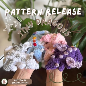 Puede incluir: Cuatro pequeños dragones de crochet en diferentes colores: blanco, azul claro, rosa y morado. Los dragones están sostenidos en las manos de una persona. El texto "PATTERN RELEASE TINY DRAGONS" está escrito en blanco sobre un fondo negro.