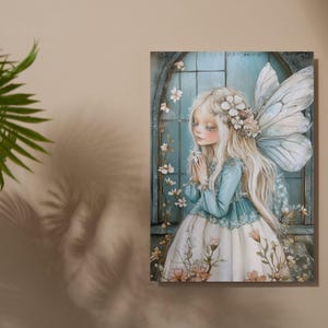 May include: A canvas print depicting a fairy with long blonde hair, wearing a blue and white dress, and large, delicate wings. The fairy is set against a backdrop of a blue window with floral accents. The artwork has a soft, ethereal quality.