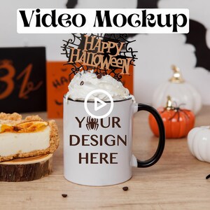 Puede incluir: Taza de cerámica blanca con asa negra, con el texto "YOUR DESIGN HERE" y un pequeño gráfico de araña. La taza está coronada con crema batida y un letrero de madera que dice "Happy Halloween". La taza está rodeada de pequeñas calabazas blancas y naranjas y arañas negras.