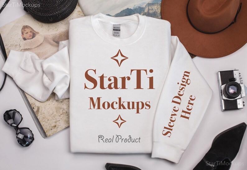 Pu&ograve; includere: Felpa bianca a maniche lunghe con un design di testo marrone che dice "StarTi Mockups" e "Sleeve Design Here" sulla manica. Il testo &egrave; centrato sulla felpa e ha un design a stella sopra e sotto il testo. Il testo "Real Product" &egrave; sotto il design a stella.