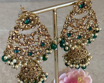 Puede incluir: Un par de pendientes colgantes de tono dorado con piedras verdes y marrones y perlas blancas. Los pendientes tienen forma de lágrima y están decorados con detalles intrincados.