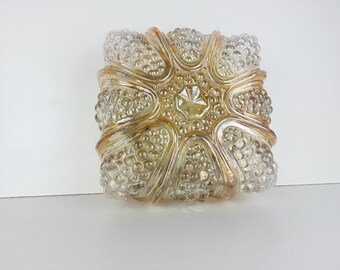 May include: A clear glass bowl with a textured surface and a gold iridescent finish. The bowl has a starburst design with six points.