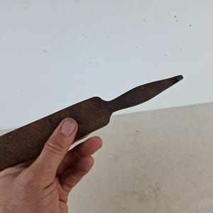 May include: A rusty metal tool with a long, flat blade and a pointed tip.