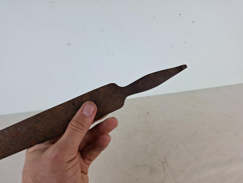 May include: A rusty metal tool with a long, flat blade and a pointed tip.