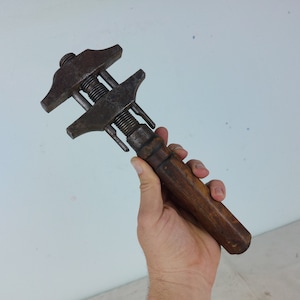 Könnte beinhalten: Ein vintage verstellbarer Schraubenschlüssel mit einem Holzgriff. Der Schraubenschlüssel hat einen Metallkopf mit silberner Oberfläche und einen schwarzen Griff.
