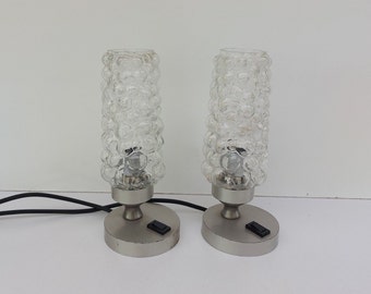 May include: Two silver table lamps with clear bubble glass shades and black cords. Each lamp has a switch on the base.