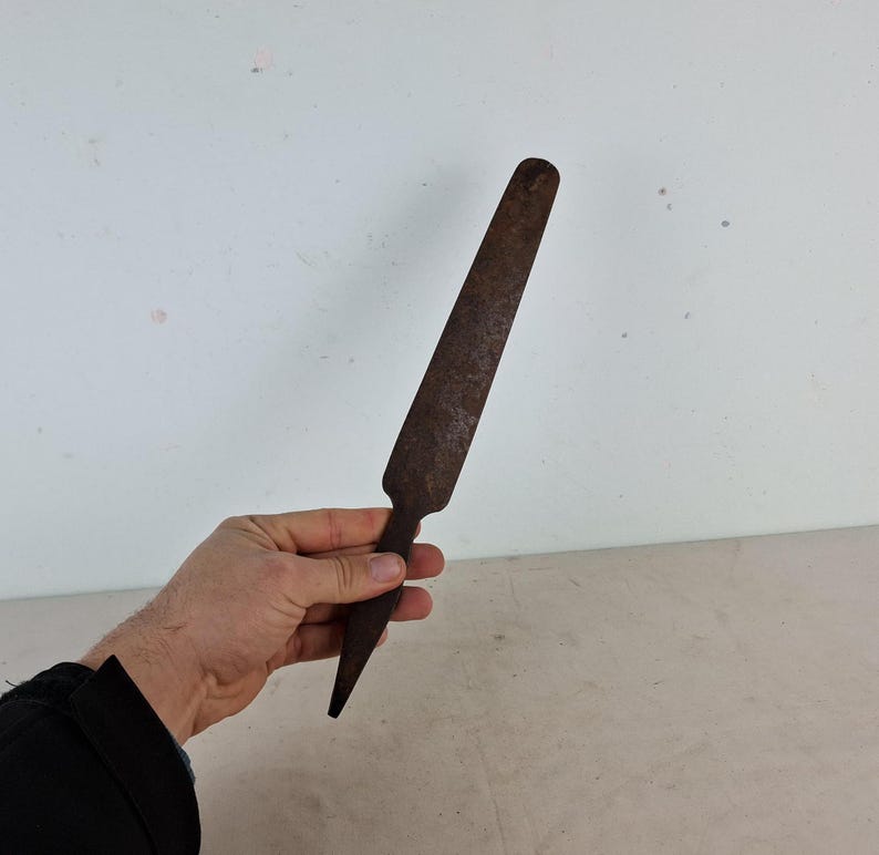 May include: A rusty metal tool with a long, thin blade and a pointed tip. The tool is about 12 inches long.