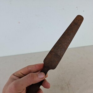 May include: A rusty metal knife with a long, thin blade and a rounded handle.