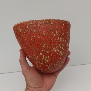 May include: A red ceramic planter with a textured surface. The planter has a speckled pattern with a light brown colour.