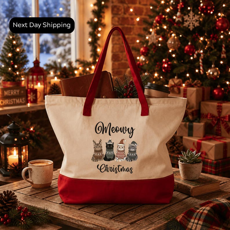 A red and white tote bag with a Christmas-themed design, featuring cats and the text "Merry Christmas" on it, placed on a wooden surface.
