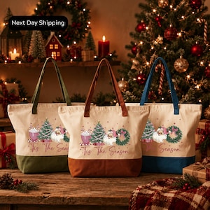 three tote bags with Christmas-themed designs, placed on a wooden surface in front of a decorated Christmas tree.