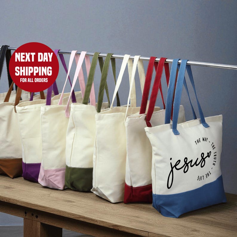 A row of colorful tote bags hanging on a rack, with a sign indicating next day shipping for all orders.