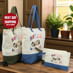 a set of three tote bags and a small bag, all with the same design and color scheme. The bags are white with blue trim and have a racing car design printed on them. The bags are placed on a wooden surface, and there are potted plants in the background.