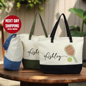two tote bags with personalized names on them, placed on a wooden table.