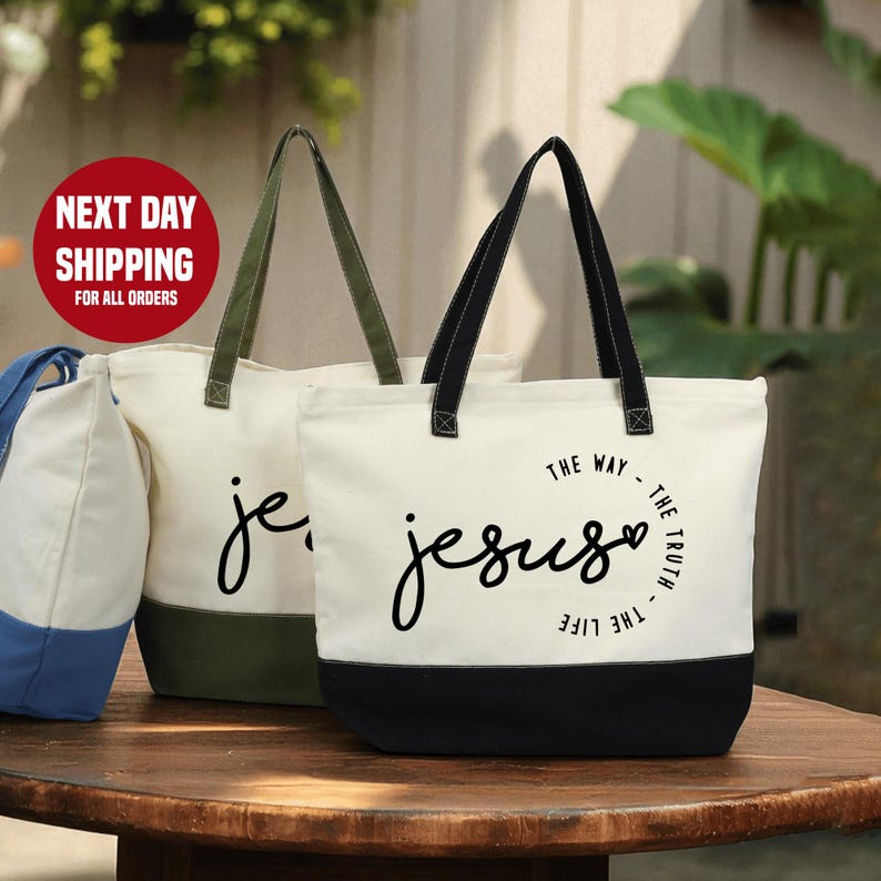 two tote bags with the text "The way - The truth - The life - The life" printed on them, placed on a wooden surface.