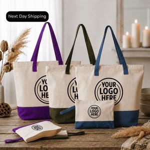 a collection of tote bags and a small bag, all featuring the same logo design. The bags are arranged on a wooden surface, with some candles and dried flowers in the background. The text "Next Day Shipping" is visible, indicating that the items are ready for immediate delivery.