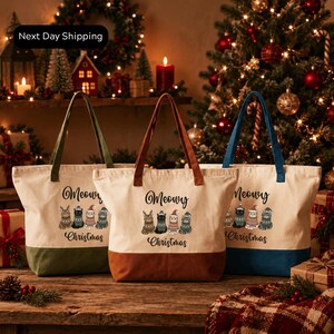 three tote bags with Christmas-themed designs, placed on a wooden surface in front of a decorated Christmas tree.