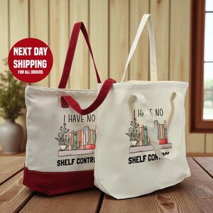 Two tote bags with the text "I HAVE NO SHELF CONTROL" printed on them, placed on a wooden surface.