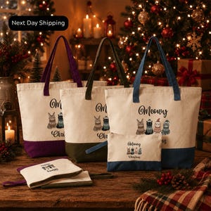 a collection of Christmas-themed tote bags and a small bag set, all with the text "Meowvy" printed on them. The bags are arranged on a wooden surface, with a Christmas tree and other holiday decorations visible in the background.