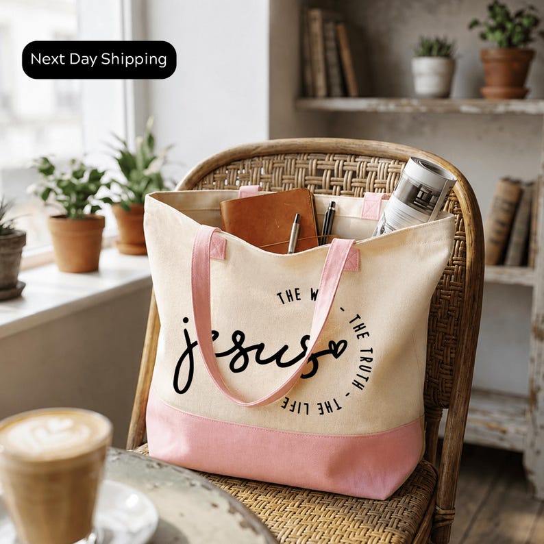 A beige tote bag with the text "The World Jesus LIVES THE TRUTH" printed on it, sitting on a wicker chair in a room with potted plants and a window.