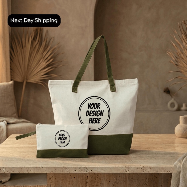 A large white tote bag with a green trim and a smaller white bag with a similar design are displayed on a wooden table.