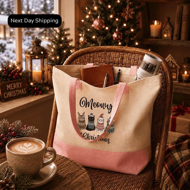 A cozy Christmas scene with a wicker chair, a coffee cup, and a tote bag with a cat design. The tote bag has a pink trim and the text "Meowvy Christmas" printed on it. In the background, there is a Christmas tree with lights, and other holiday decorations such as a lantern and a gift box.