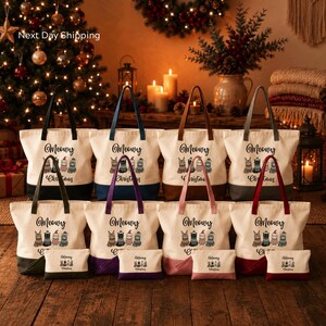 A collection of white tote bags with the text "Merry Christmas" printed on them, arranged in a grid-like pattern on a wooden surface. In the background, there is a Christmas tree and other holiday decorations, creating a festive atmosphere.