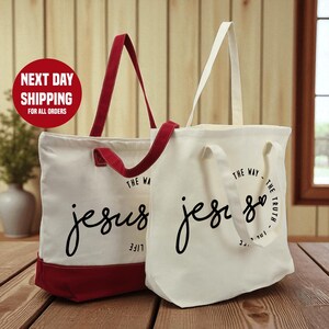 Two tote bags with the text "The Way Jesus" printed on them, placed on a wooden surface.