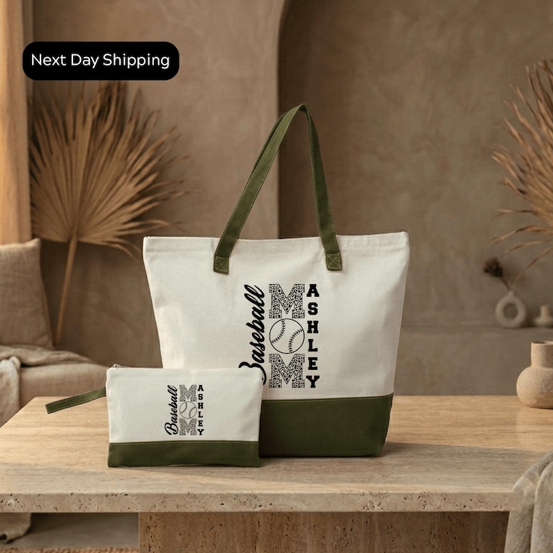 A white tote bag with a green trim and a smaller white bag with a similar design are displayed on a wooden table.
