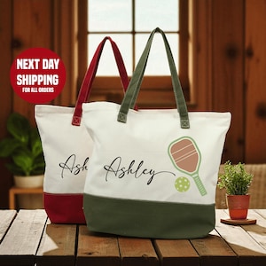 Two personalized tote bags with the name "Ashley" printed on them, placed on a wooden surface.