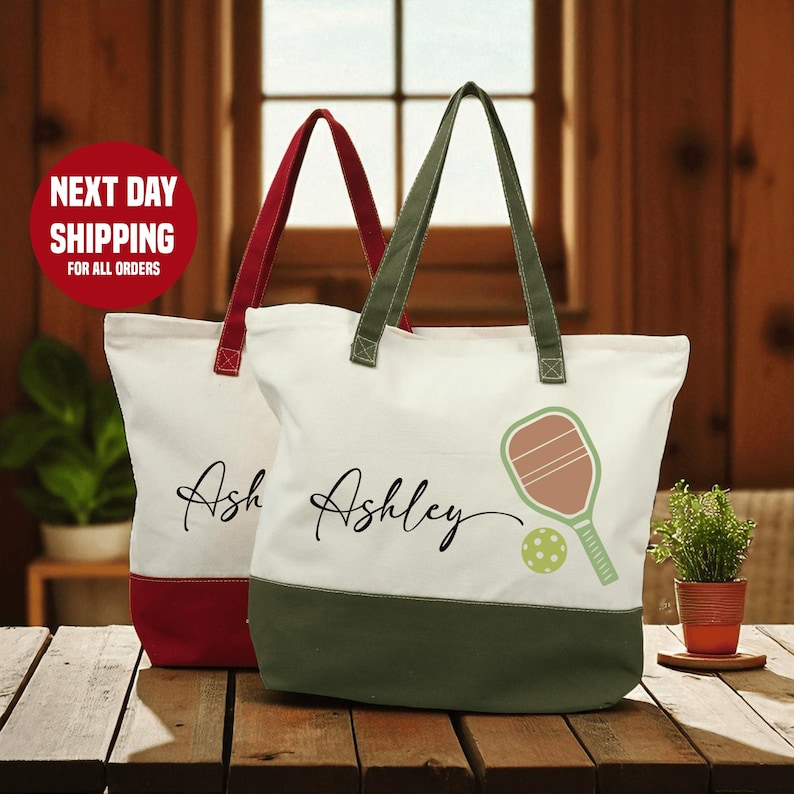 Two personalized tote bags with the name "Ashley" printed on them, placed on a wooden surface.