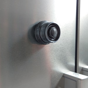May include: A black plastic refrigerator door handle with a round, textured knob.
