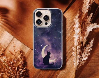 Puede incluir: Una funda de teléfono con un diseño de noche estrellada, una luna creciente y una silueta de gato negro. La funda tiene un fondo azul oscuro y morado con estrellas blancas. La funda del teléfono está sobre una superficie de madera.