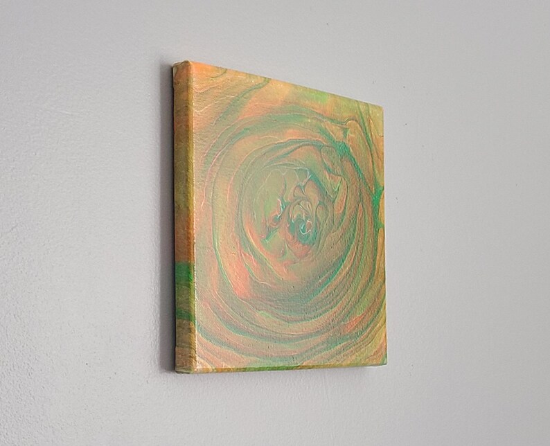 May include: Abstract painting on canvas with swirling green and orange colors. The painting has a circular pattern with a dark center.