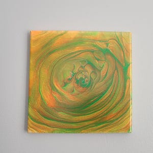 May include: Abstract painting on canvas with swirling green and orange colors. The colors create a circular pattern that resembles a flower.