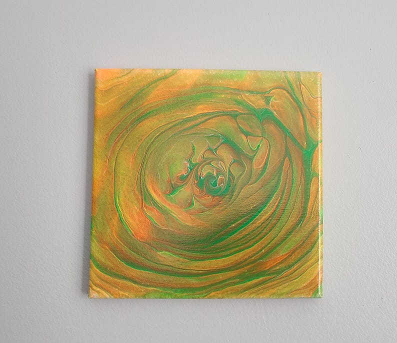 May include: Abstract painting on canvas with swirling green and orange colors. The colors create a circular pattern that resembles a flower.