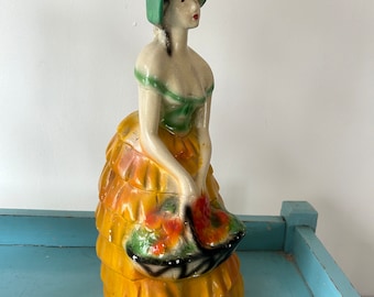 Figura grande de yeso de los años 30 de una dama con cesta de flores y gorro.
