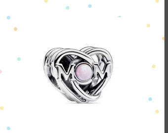 May include: Silver charm in the shape of a heart with the word "MOM" intertwined. The heart has a white opal in the center.
