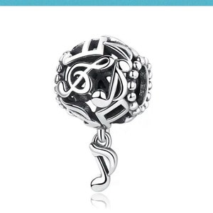 May include: A silver charm with a musical theme. The charm is a sphere with cut-out musical notes and a dangling eighth note. The charm is detailed with a treble clef and other musical symbols.