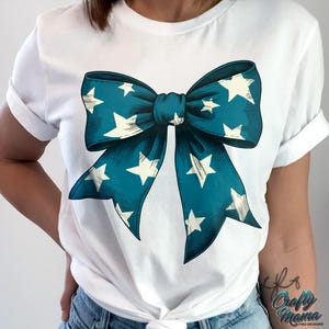 May include: White t-shirt with a teal blue bow with white stars printed on it.