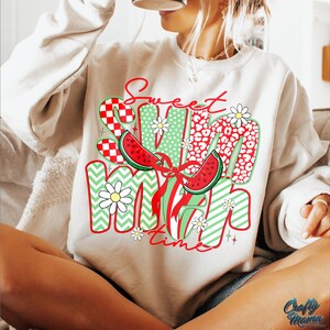 May include: A white sweatshirt with the text "Sweet Summer Time" in red and green letters. The letters are decorated with watermelon slices, daisies, and checkered patterns.
