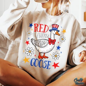 May include: A white sweatshirt with a red, white, and blue goose wearing a red, white, and blue hat. The text "Red White & Goose" is printed on the sweatshirt.