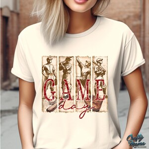 K&ouml;nnte beinhalten: Cremefarbenes T-Shirt mit Baseball-Motiv. Das Design zeigt vier Baseballspieler und die Worte "GAME DAY" in einer rot karierten Schriftart. Das Bild hat einen Vintage-Look mit Baseballschl&auml;gern und -handschuhen.