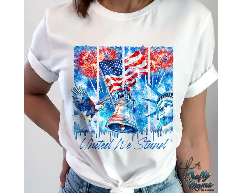 Pu&ograve; includere: Maglietta bianca con un design ad acquerello che presenta una bandiera americana, un'aquila calva, la Statua della Libert&agrave; e una campana. Il design &egrave; circondato da fuochi d'artificio e il testo "United We Stand".