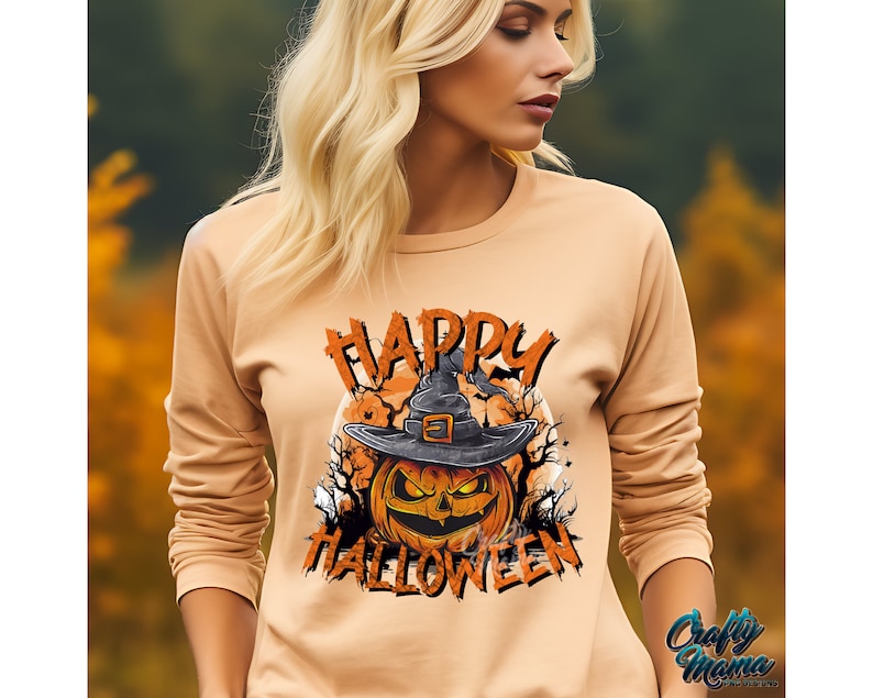 Peut inclure: Un sweat-shirt &agrave; manches longues de couleur orange clair avec un imprim&eacute; graphique d'une citrouille portant un chapeau de sorci&egrave;re. Le texte "Happy Halloween" est imprim&eacute; sur le sweat-shirt.